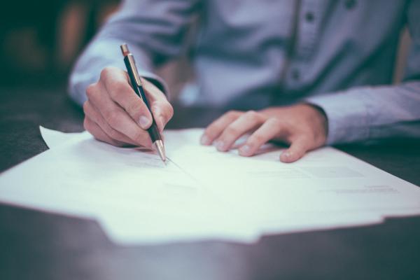 Person holding a pen over documents