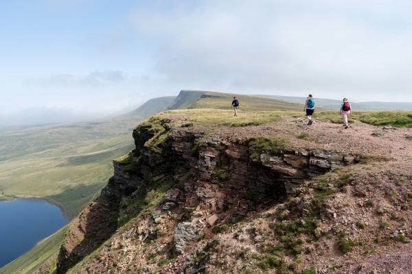 3 cerddwr ar fynydd arfordirol yng Nghymru