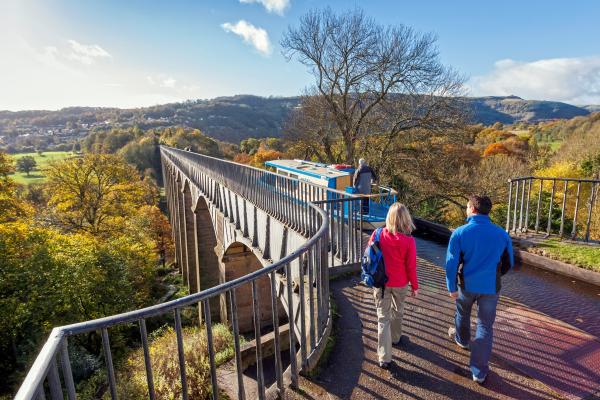 pobl yn croesi traphont ddŵr a chamlas ar droed ac mewn cwch