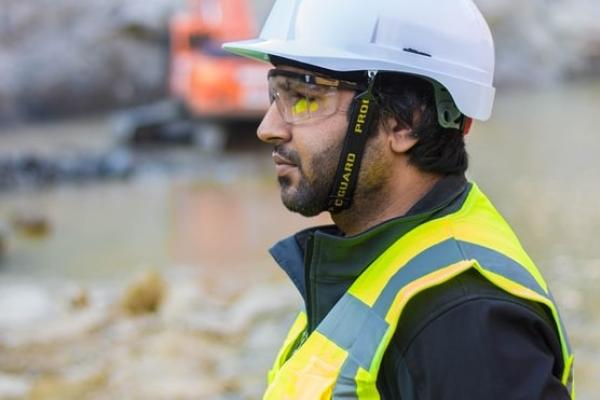 Dyn yn gwisgo siwt ddiogelwch ar y safle adeiladu